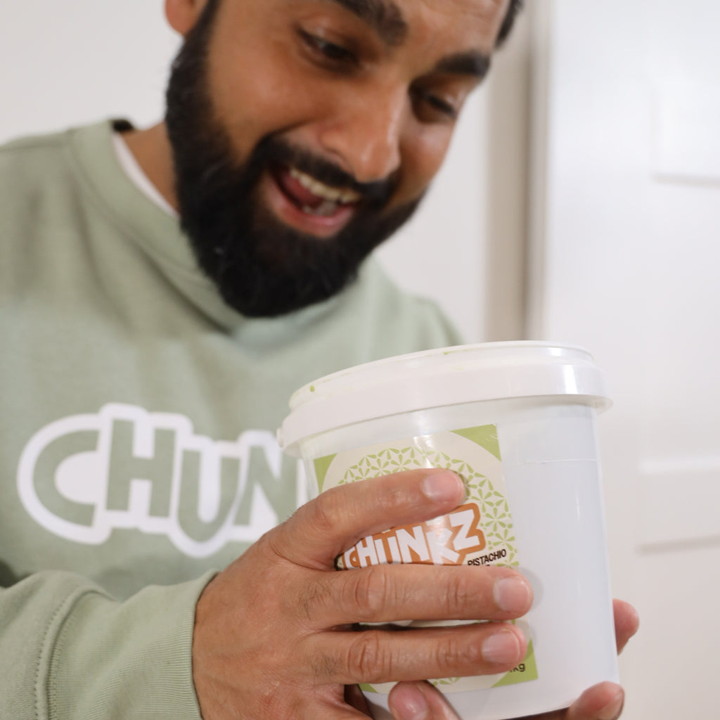 Reggie, founder of GetChunkz.com, smiling while holding a 1kg tub of Chunkz Pistachio Kadayif Crème – proud moment with the original Dubai chocolate filling